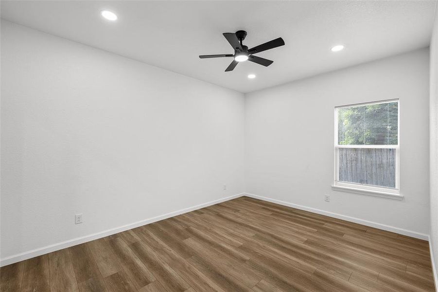 Neutral-toned room featuring wood-finish flooring, a ceiling fan with integrated lighting, and recessed ceiling lights Neutral-toned room featuring wood-finish flooring, a ceiling fan with integrated lighting, and recessed ceiling lights