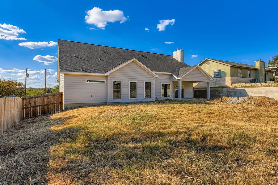 Back of house featuring a patio area, a fenced backyard, a shingled roof, and a chimney