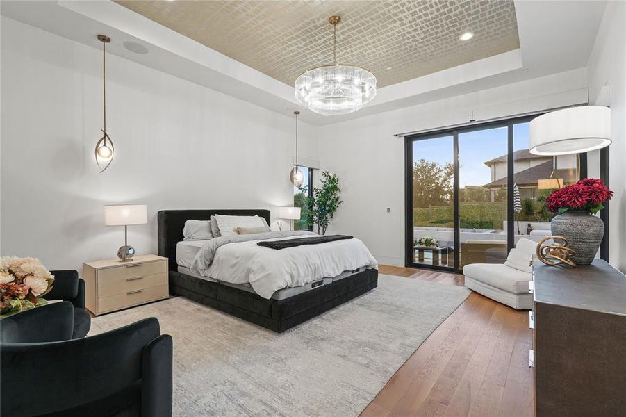 Bedroom with a tray ceiling, wood finished floors, and access to exterior Bedroom with a tray ceiling, wood finished floors, and access to exterior