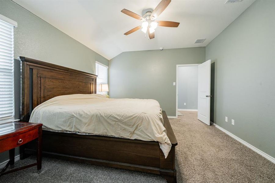 Bedroom featuring carpet flooring, vaulted ceiling, and a ceiling fan Bedroom featuring carpet flooring, vaulted ceiling, and a ceiling fan