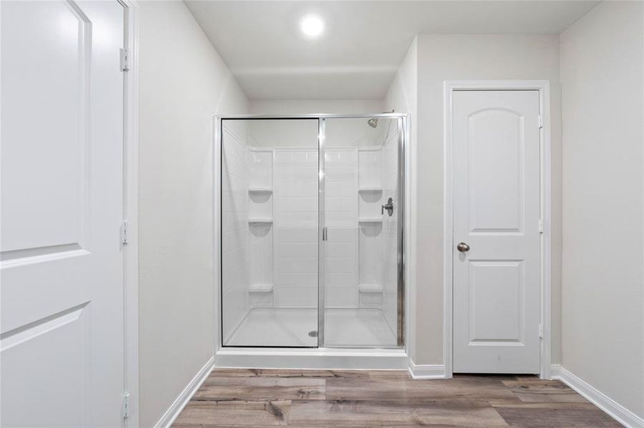Bathroom featuring wood finished floors, a stall shower, and baseboards