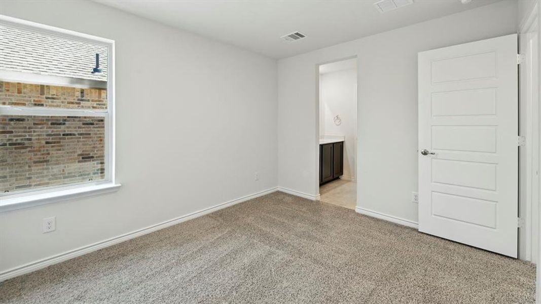 Empty room with light colored carpet and baseboards