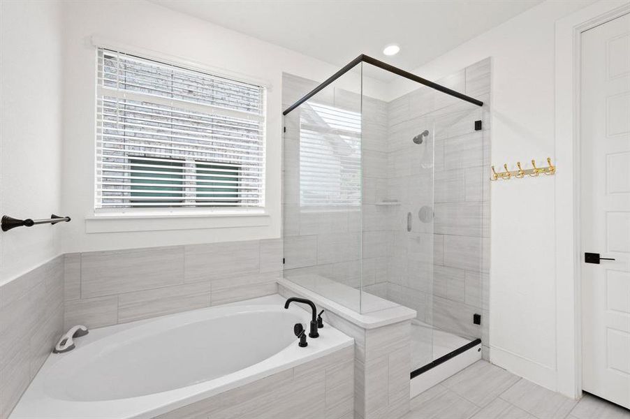 Contemporary bathroom featuring a corner soaking tub with matte black fixtures, a walk-in shower with glass enclosure and bench, light-toned tile flooring, and white walls Contemporary bathroom featuring a corner soaking tub with matte black fixtures, a walk-in shower with glass enclosure and bench, light-toned tile flooring, and white walls