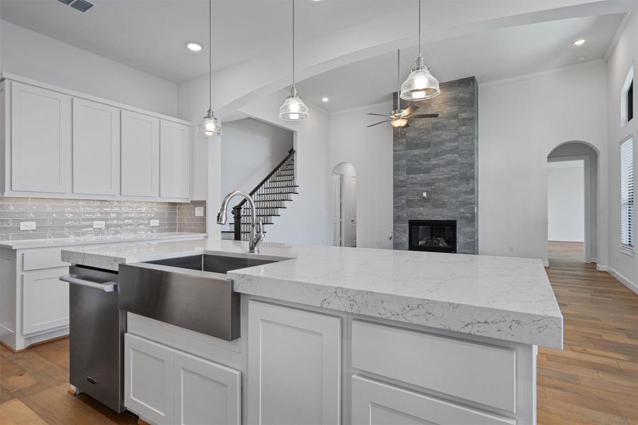 Kitchen island featuring a stainless steel farmhouse sink, white shaker cabinetry, and light-toned countertops