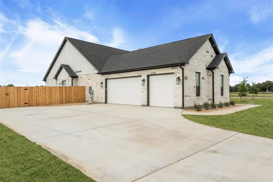 View of side of home featuring stone siding, a shingled roof, concrete driveway, a garage, and board and batten siding View of side of home featuring stone siding, a shingled roof, concrete driveway, a garage, and board and batten siding