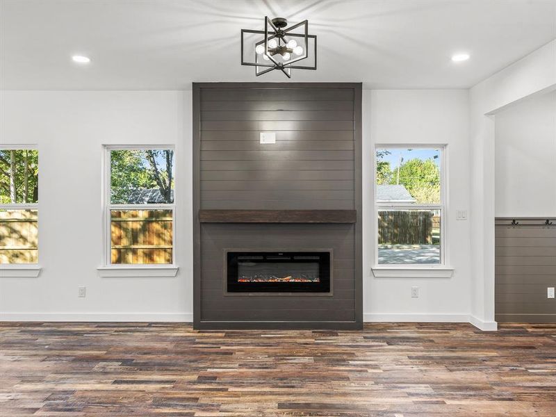 Unfurnished living room with recessed lighting, dark wood finished floors, and a large fireplace