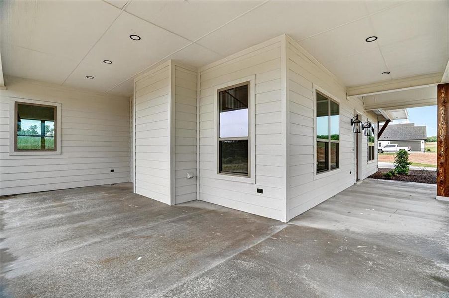 Covered patio featuring a concrete surface, white horizontal siding, recessed ceiling lighting, and exterior wall sconces
