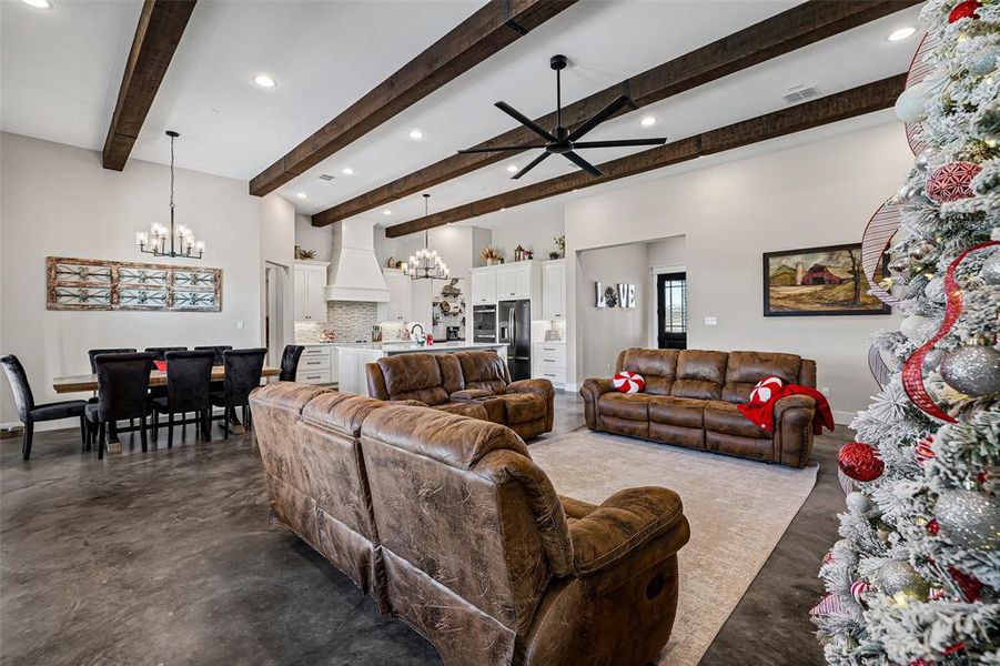 Living room with a chandelier, concrete floors, a ceiling fan, recessed lighting, and beam ceiling Living room with a chandelier, concrete floors, a ceiling fan, recessed lighting, and beam ceiling