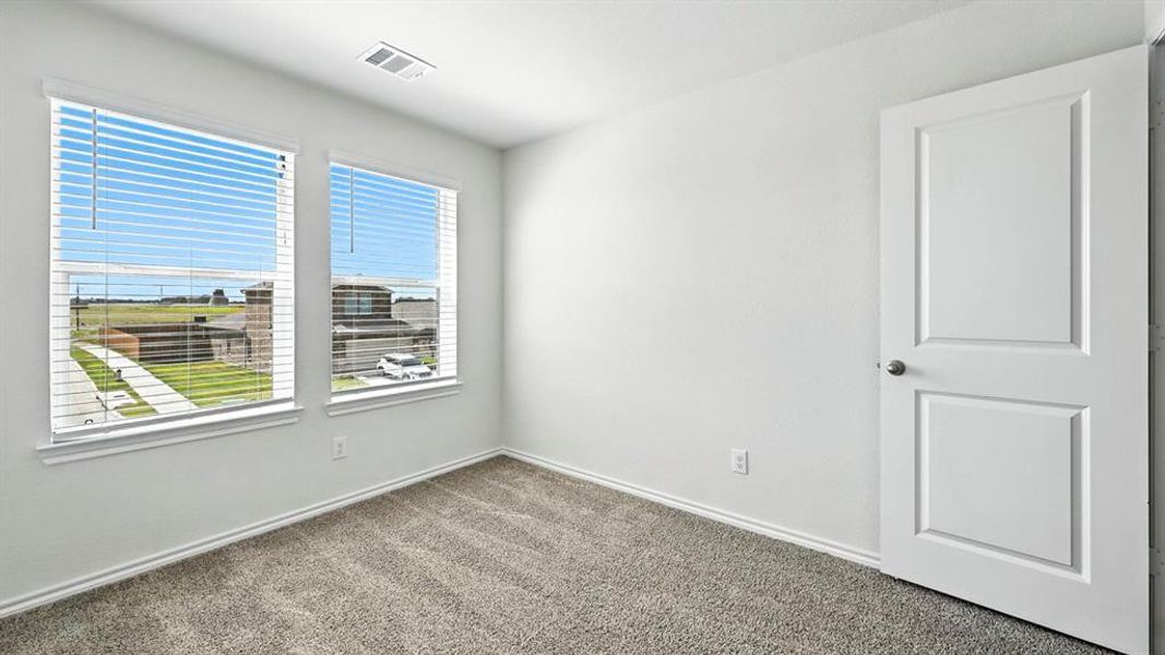 Bright room featuring two windows with blinds, gray carpeting, a paneled door, and white baseboards