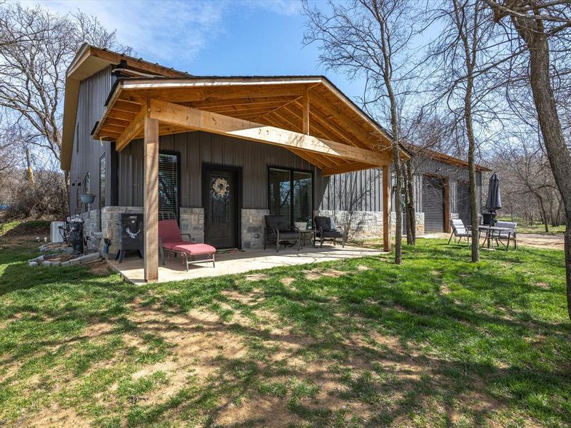 featuring a patio area, stone siding, and a lawn