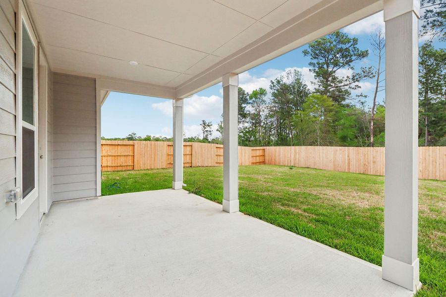The backyard features a pristine concrete patio slab, providing a clean and durable foundation for your customized outdoor retreat. This functional extension of the home serves as the perfect transition between the indoor living space and the expansive green lawn.