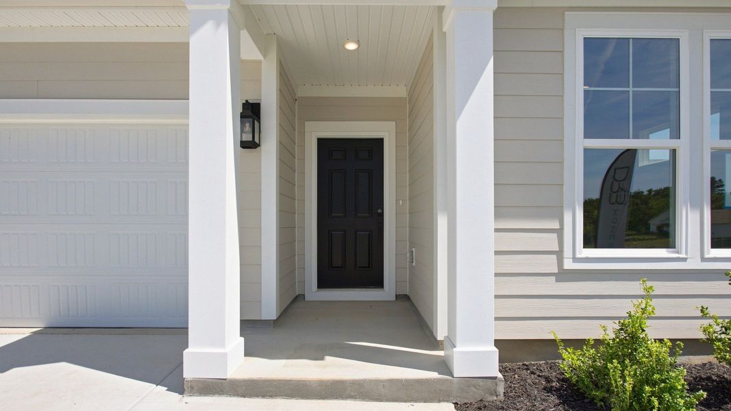 Covered front patio entry next to garage with painted support beams