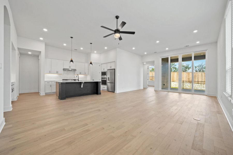 Unfurnished living room with light wood-type flooring, a ceiling fan, and recessed lighting
