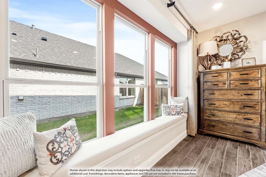 Bedroom window seat with decorative pillows, wood dresser, and large windows overlooking backyard Bedroom window seat with decorative pillows, wood dresser, and large windows overlooking backyard