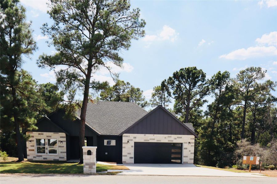 Modern farmhouse style home featuring board and batten siding, a shingled roof, driveway, and an attached garage