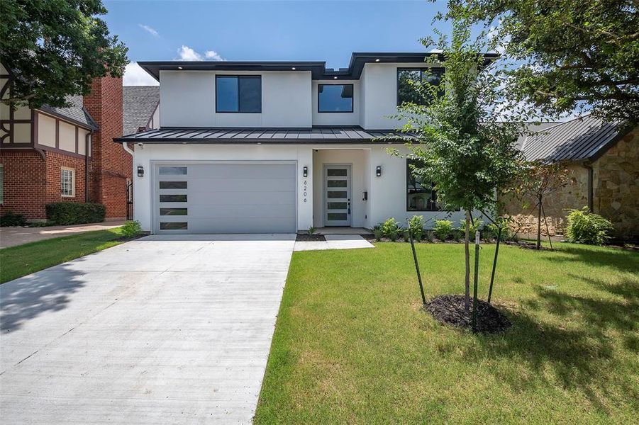 View of front facade featuring a garage and a front lawn