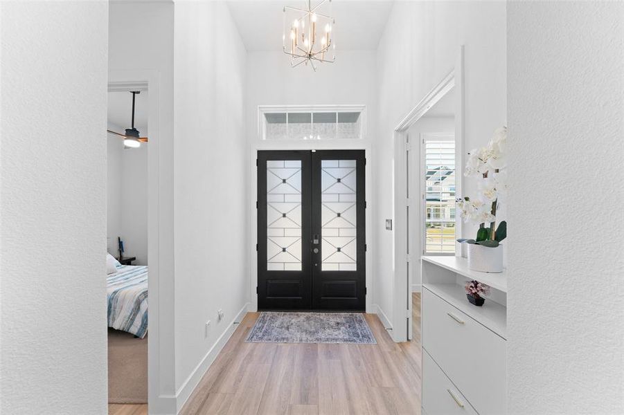 Entryway with light wood finished floors, a chandelier, a textured wall, and ceiling fan Entryway with light wood finished floors, a chandelier, a textured wall, and ceiling fan