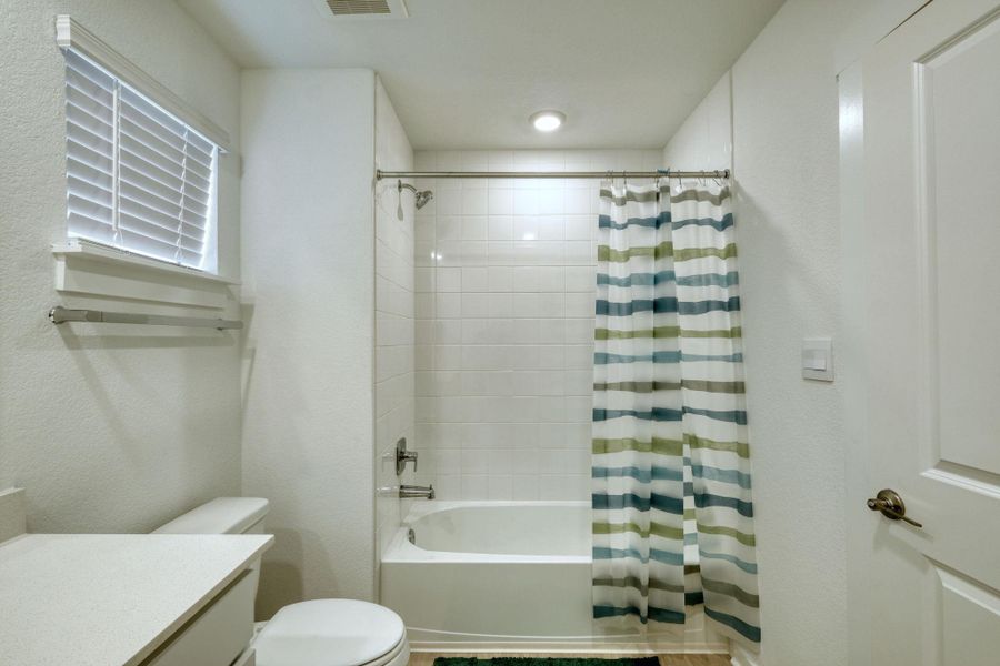 Bathroom featuring visible vents, vanity, shower / bath combination with curtain, and toilet