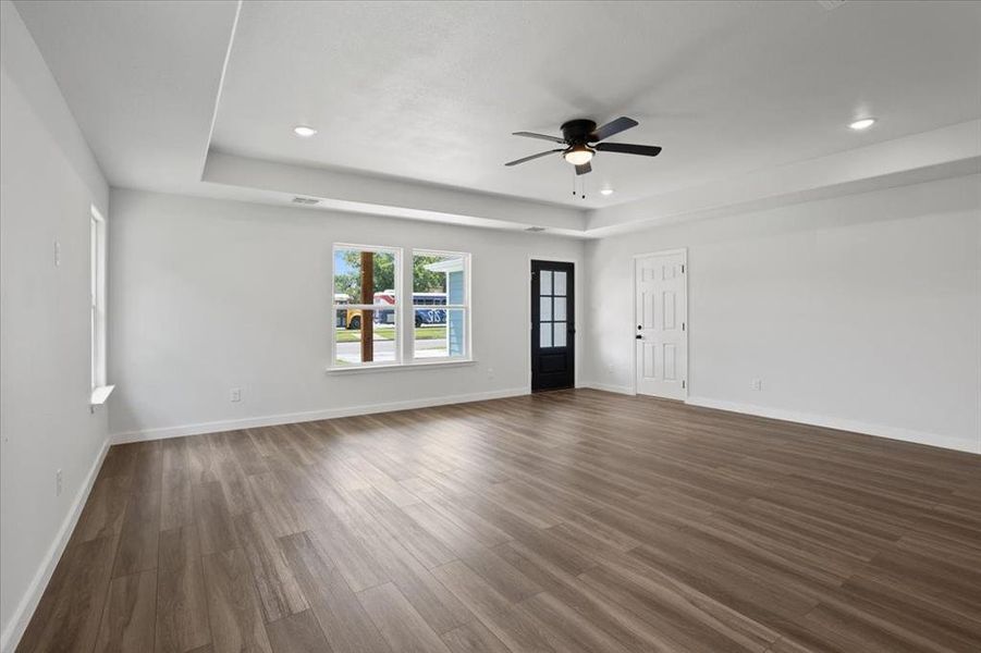 Unfurnished living room with a raised ceiling, ceiling fan, and hardwood / wood-style floors