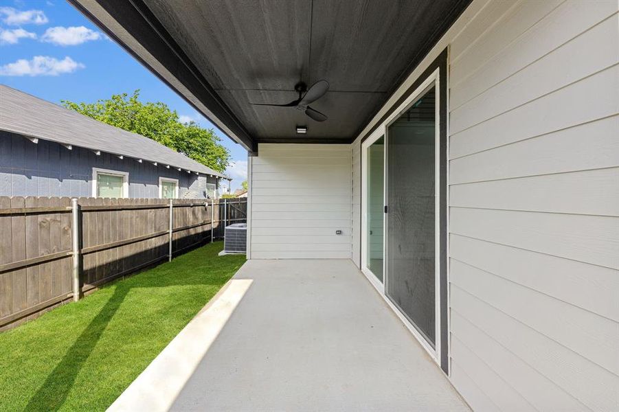 The property features an outdoor patio with an overhead fan, a sliding glass door, and a grassy area enclosed by a wooden fence The property features an outdoor patio with an overhead fan, a sliding glass door, and a grassy area enclosed by a wooden fence