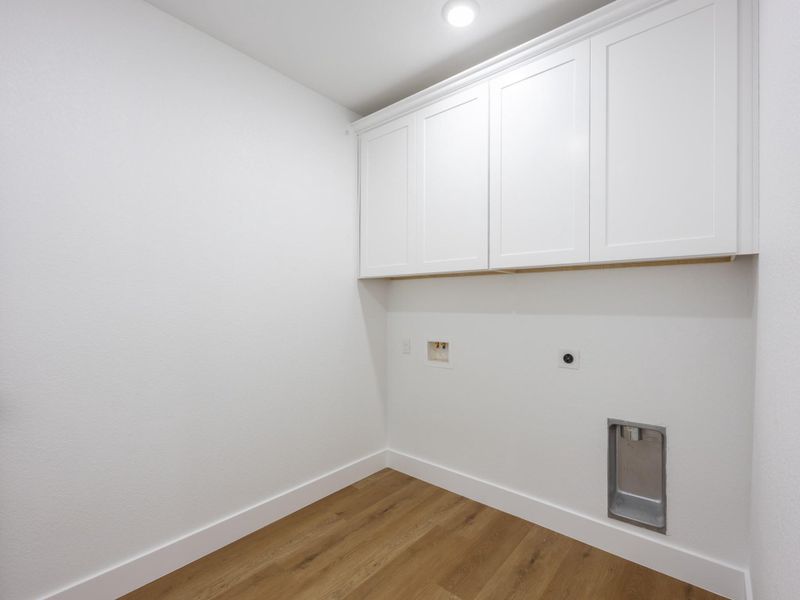 This bright laundry room offers upper cabinets for storage and all necessary utility hookups, making laundry day efficient and organized. This bright laundry room offers upper cabinets for storage and all necessary utility hookups, making laundry day efficient and organized.