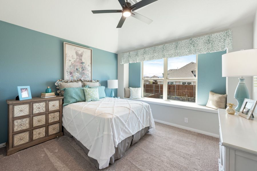 Bedroom with teal walls, vaulted ceiling, ceiling fan, window seat, and carpeted floors