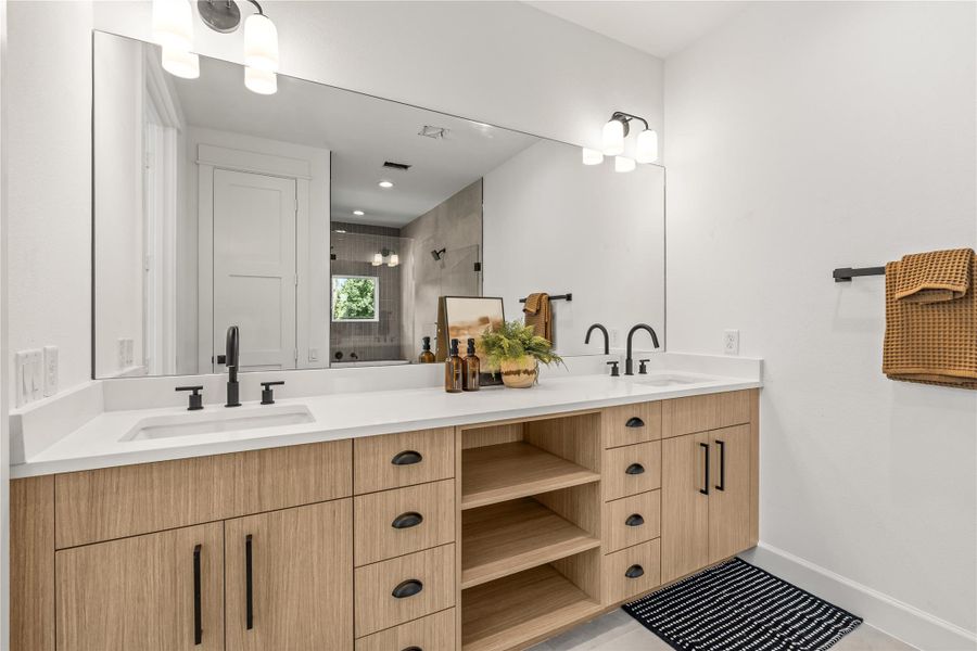 Perspective view of the primary bathroom vanity highlighting the large frameless mirror and modern dual light fixtures. Perspective view of the primary bathroom vanity highlighting the large frameless mirror and modern dual light fixtures.