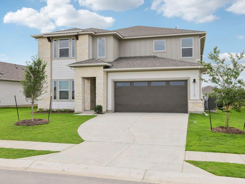 Prairie-style house featuring stone siding, concrete driveway, board and batten siding, and a front lawn Prairie-style house featuring stone siding, concrete driveway, board and batten siding, and a front lawn