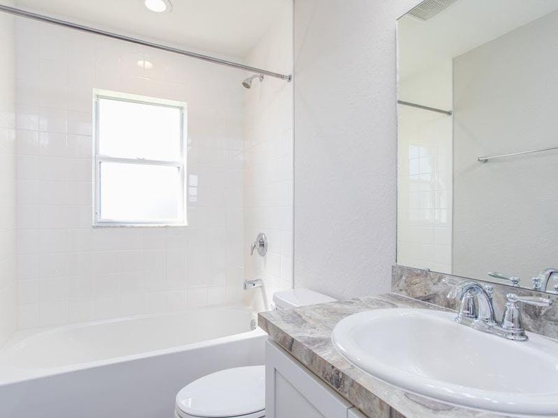 A hall bath serves the secondary bedrooms and guests. Photo showcases a home with similar finishes. Colors and design options in actual home for sale may differ.