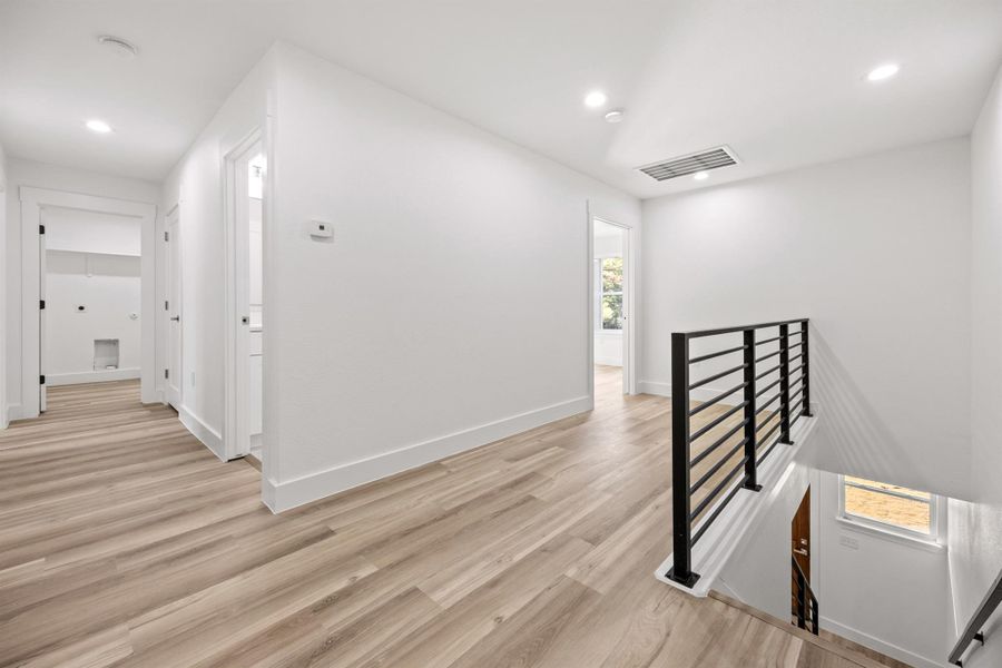 Corridor featuring an upstairs landing, light wood-style floors, and recessed lighting