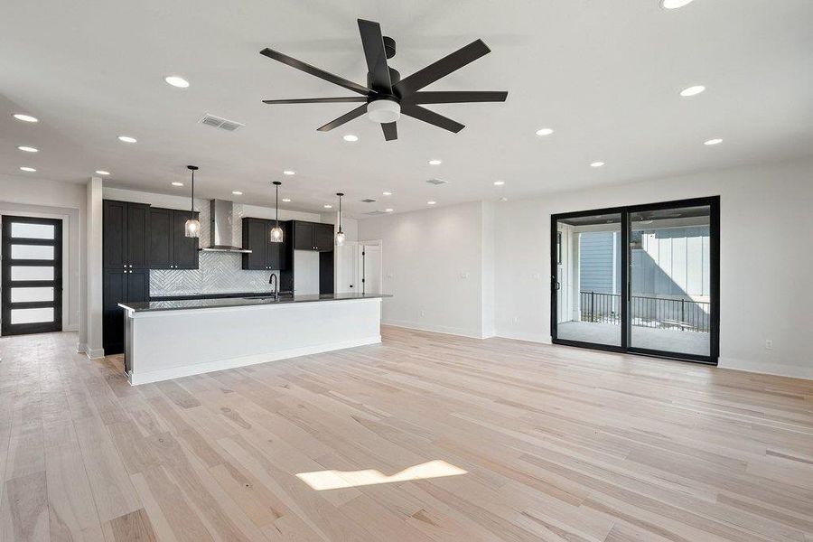 Unfurnished living room featuring a ceiling fan, light wood-type flooring, and recessed lighting