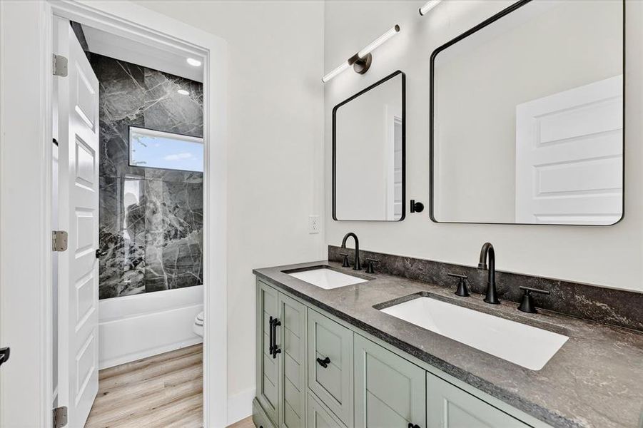Bathroom featuring a double vanity with a gray stone countertop and two integrated sinks