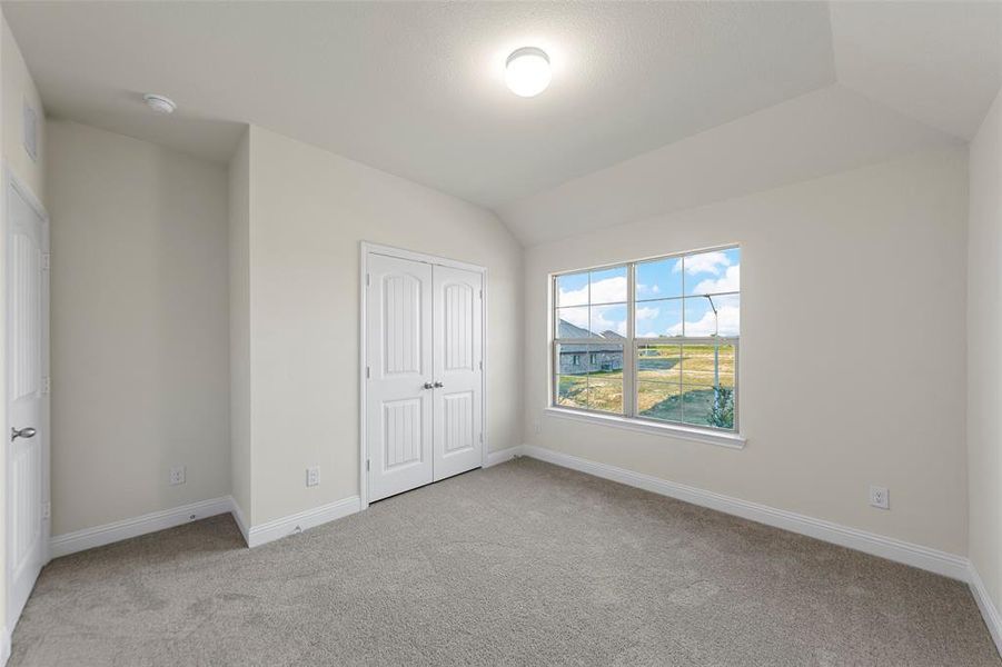 Unfurnished bedroom featuring light carpet, lofted ceiling, and a closet Unfurnished bedroom featuring light carpet, lofted ceiling, and a closet