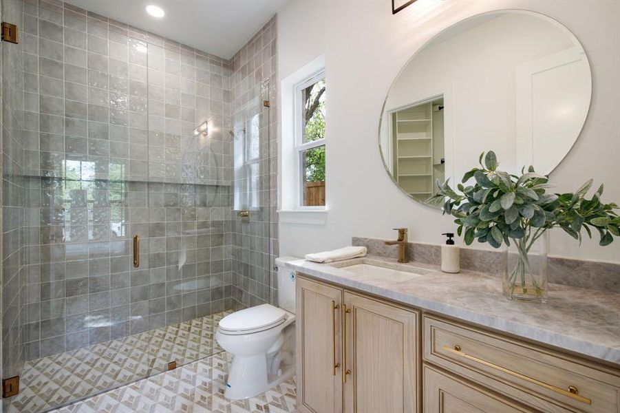 Bathroom featuring a frameless glass shower enclosure with square gray wall tiles and patterned floor tiles Bathroom featuring a frameless glass shower enclosure with square gray wall tiles and patterned floor tiles