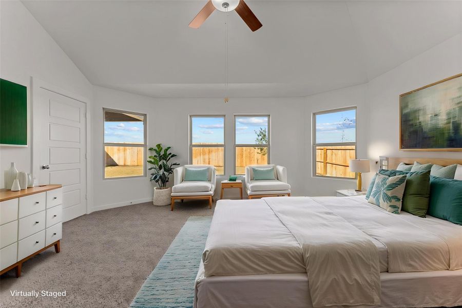 An airy primary bedroom suite features large windows, soft carpeting, and a modern ceiling fan.
