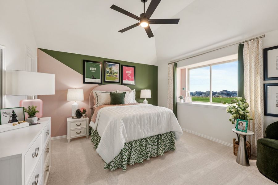 Bedroom with vaulted ceiling, ceiling fan, green and pink accent wall, and large window with neighborhood view