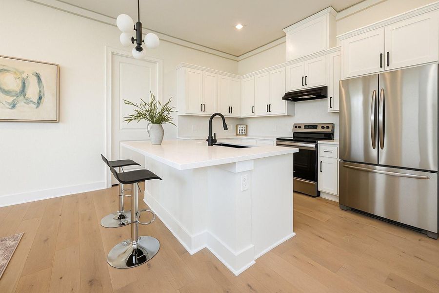 Modern kitchen with direct access to the garage, featuring a spacious island, white cabinetry, and stainless steel appliances for everyday convenience.