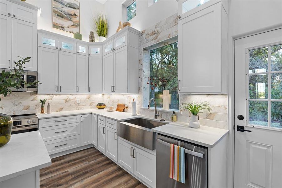 Kitchen with white cabinetry, backsplash, dark hardwood / wood-style flooring, stainless steel appliances, and sink