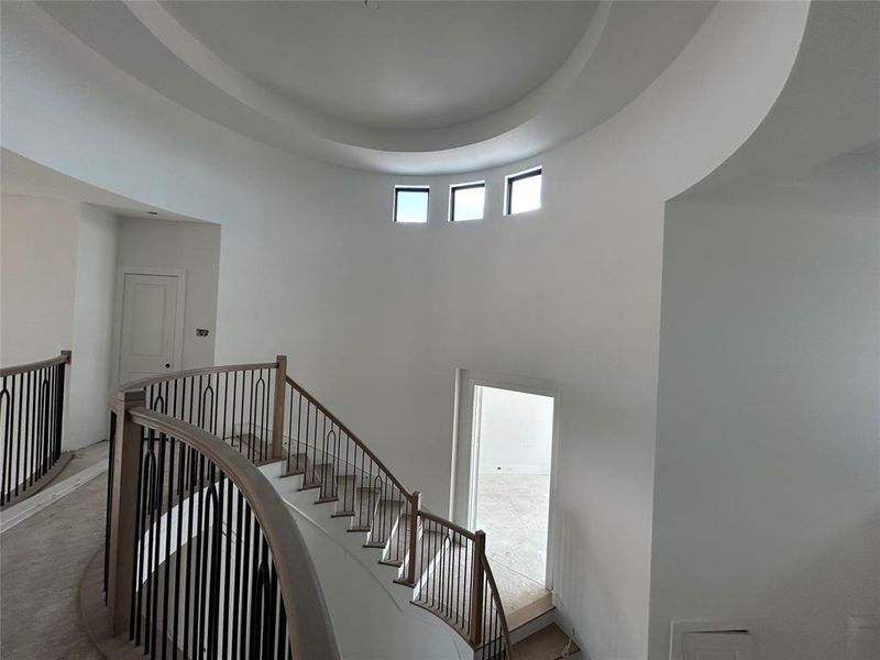 The study is nestled halfway up the gracefully curved staircase, providing a serene and elevated retreat. This location offers a unique vantage point and a sense of seclusion, perfect for focused work or quiet contemplation.