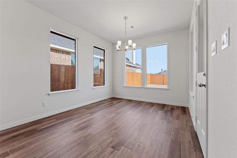 Unfurnished dining area featuring suspended lighting, dark wood finished floors, and healthy amount of natural light