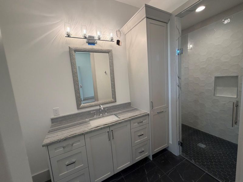 This en-suite bath, with quartzite countertops, custom cabinets, and shower, is located off the first floor study with a walk-in closet. This progress photo was taken August 11.