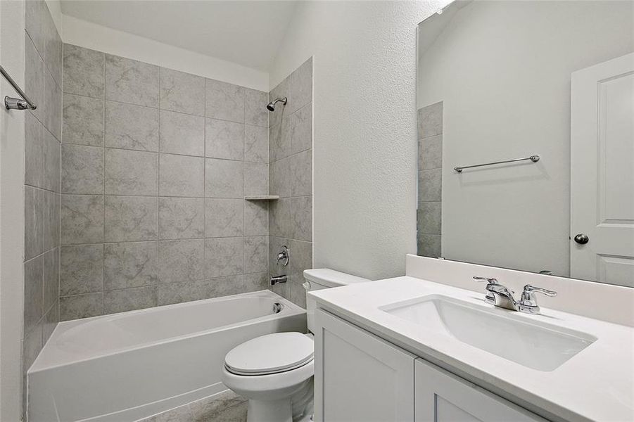 Full bathroom with tiled shower / bath, vanity, and toilet