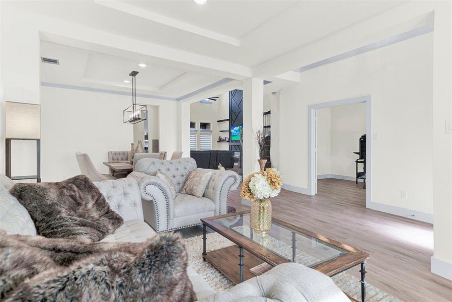 Living area with a tray ceiling, wood finished floors, recessed lighting, and a chandelier Living area with a tray ceiling, wood finished floors, recessed lighting, and a chandelier