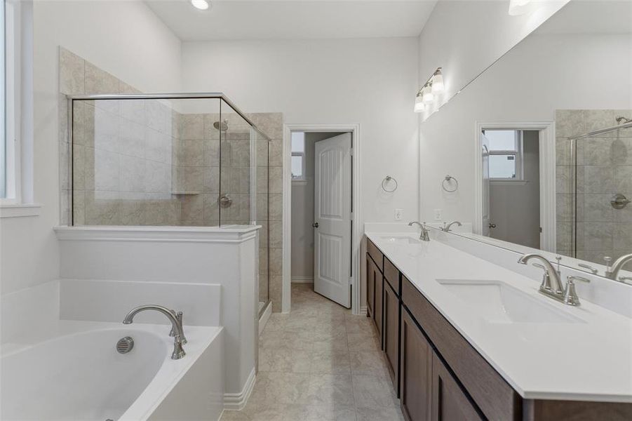 Bathroom featuring a deep soaking tub, a glass-enclosed shower with tiled walls, and a dual vanity with undermount sinks and a wide mirror