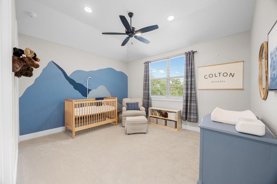 Carpeted bedroom with a crib, recessed lighting, a ceiling fan, and vaulted ceiling