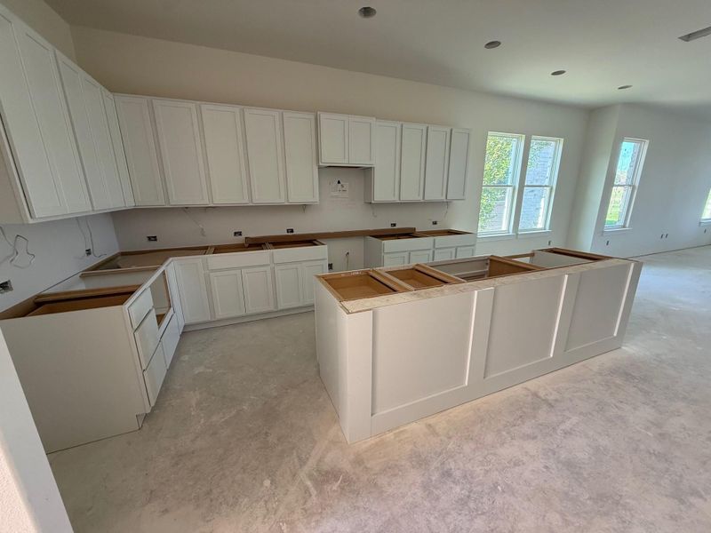 Kitchen with white cabinets, concrete flooring, and a center island
