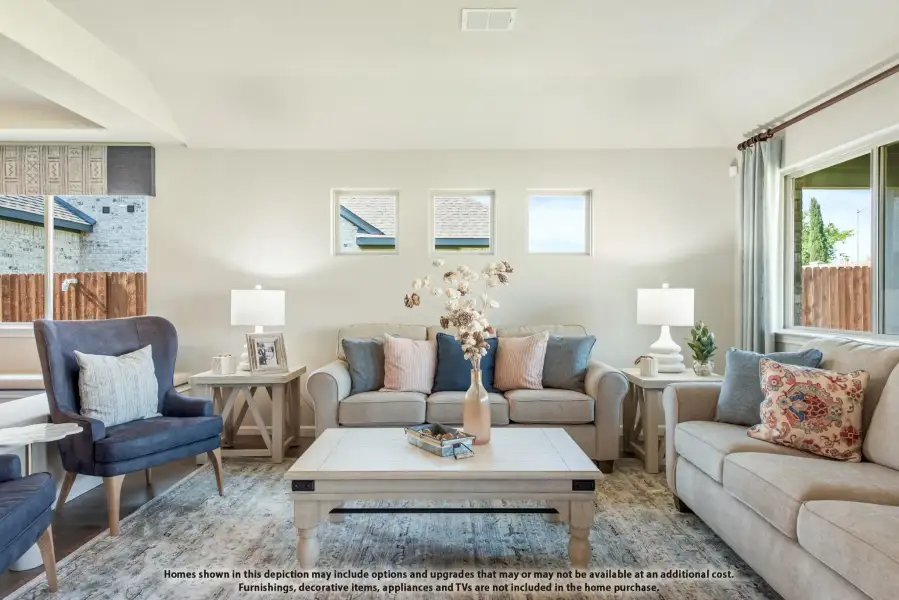 Living room with beige sofas, blue accent chair, white coffee table, and decorative pillows in blue and pink tones