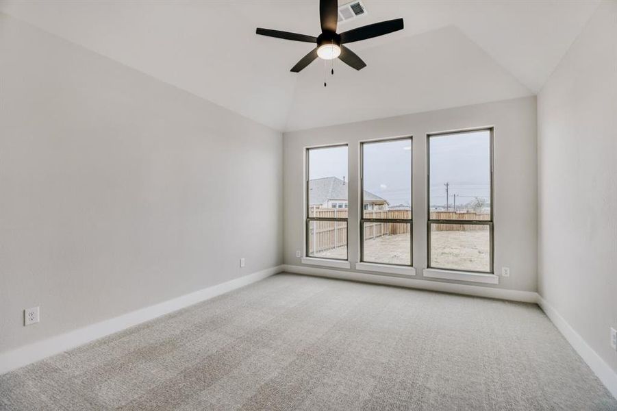 Empty room featuring light carpet, a ceiling fan, and vaulted ceiling