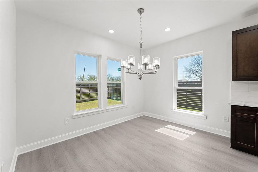 Unfurnished dining area with suspended lighting and light wood-type flooring
