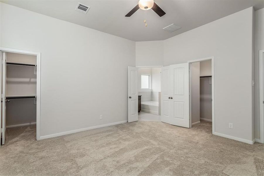 Retreat to the spacious primary bedroom, complete with large windows and a ceiling fan for comfort. The plush carpeting adds warmth, while the neutral tones create a relaxing atmosphere. The primary suite offers a private oasis with an ensuite bathroom, providing the perfect space to unwind after a long day. Photos are from another Rylan floor plan.